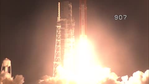 A space rocket launches vertically from the pad with a bright plume of fire.