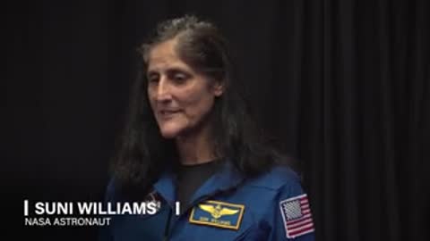 Astronaut in blue uniform with American flag patch speaks in interview format.