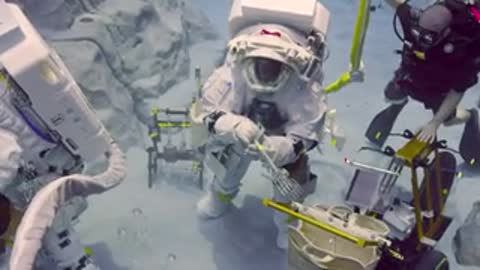 Astronaut and diver work together with equipment on underwater mockup surface.