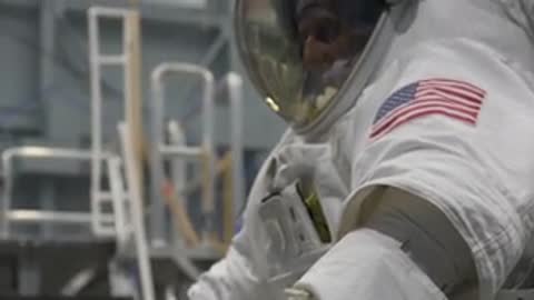 Close-up of astronaut arm and shoulder with American flag patch during spacesuit test.