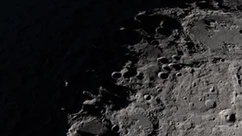 Lunar surface at night with illuminated crater highlights