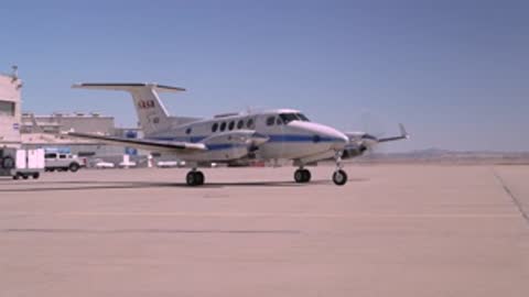 The NASA airplane taxiing on the runway during the day.