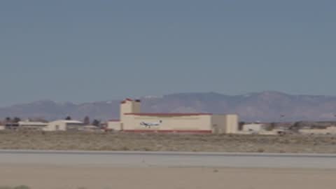 Wide view of the runway and distant buildings during daytime horizon.