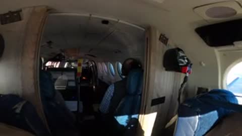 Pilot in the cockpit looking out and operating aircraft controls.