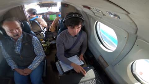 Crew members working on equipment inside the airplane cabin.