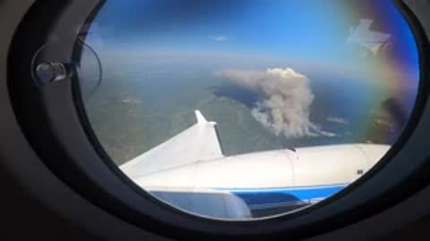 Interior and window view showing smoke rising from a wildfire below.