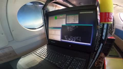 Laptop screen displaying data and graphs inside the airplane cabin.