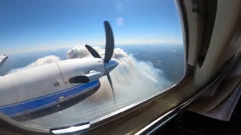 interior view of a king air airplane in flight near a wildfire, smoke visible
