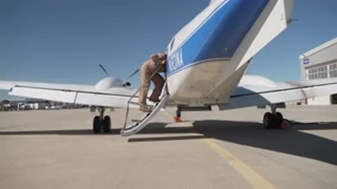 A crew member climbing the stairs to board the airplane.