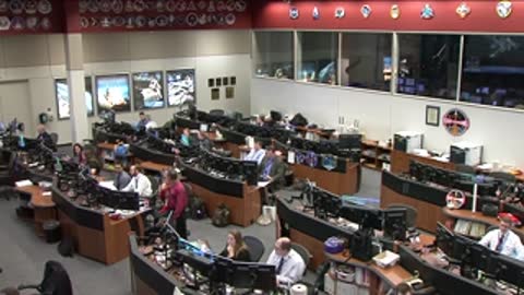 International Space Station Flight Control Room with personnel working at consoles.