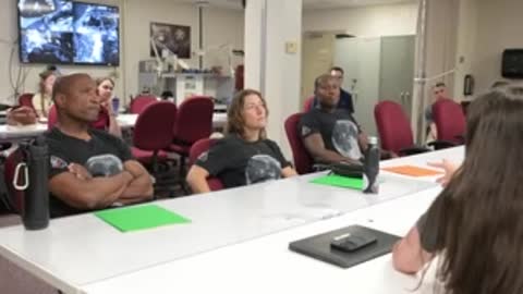 Astronauts in black shirts sitting at a conference table with documents.