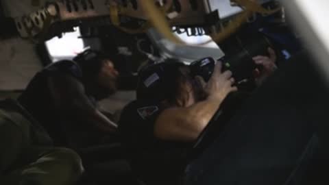 Astronauts working inside a cramped spacecraft cockpit simulator.
