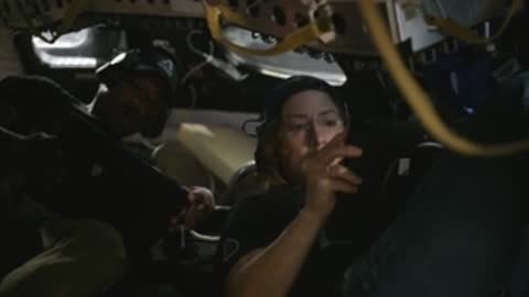 Astronaut adjusting equipment inside a dark spacecraft simulator cabin.