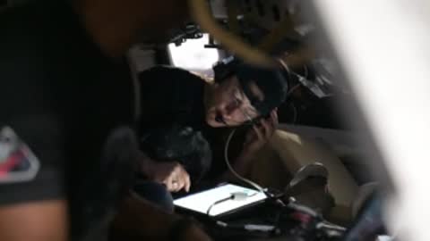 Astronaut using a tablet computer inside a spacecraft simulator cockpit.