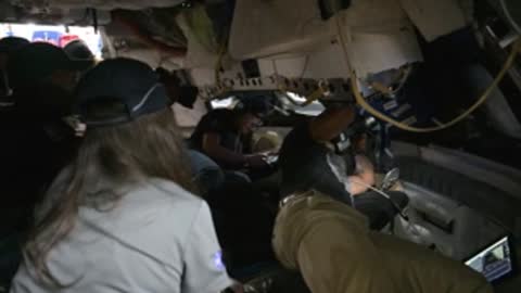 An astronaut with long hair sits inside a training simulator.
