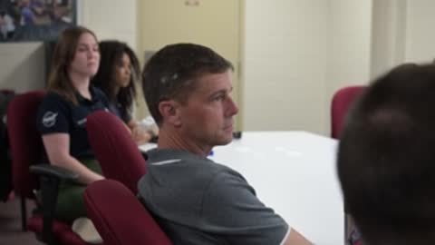 An astronaut listens attentively during a meeting in a conference room.