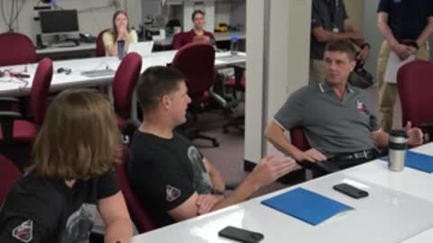 An astronaut speaks during a meeting while others listen.