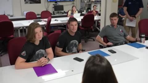 Astronauts sit at a conference table during a briefing session.