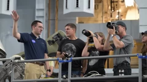 Astronauts look through camera lenses on a scaffolding platform.
