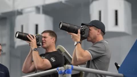 Astronauts look through telephoto camera lenses on a platform.