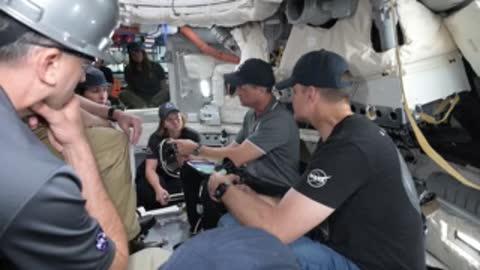 Astronauts sit inside a spacecraft simulator cockpit during training.