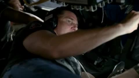 Astronaut in vehicle training simulation, reaching out.