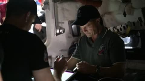 Astronauts in simulator reviewing notes on tablet.