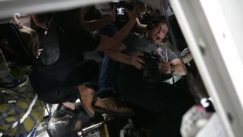 Astronaut holding equipment inside simulator during training.