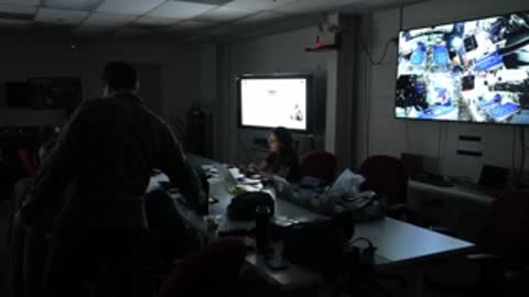 Person walking in dimly lit mission control room.