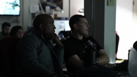 Astronauts sitting together listening in briefing room.