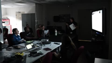 Overview of conference room with people seated during presentation.