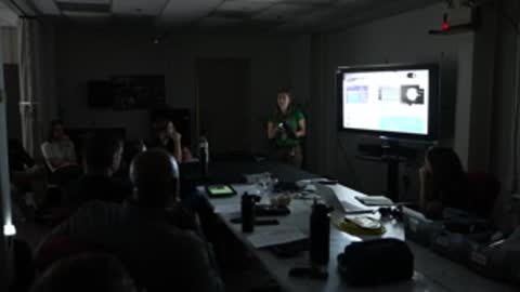 Conference room view of presentation screen and seated people.