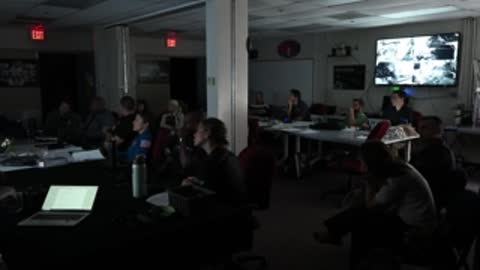 Wide view of dark conference room with illuminated desks.