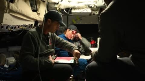 Astronauts seated inside vehicle cockpit reviewing papers.
