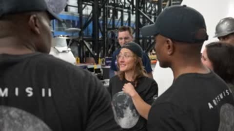 Over-the-shoulder view of astronauts talking to instructors near equipment.