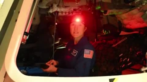 astronaut operating controls inside a spacecraft cabin, looking towards the camera, medium shot.