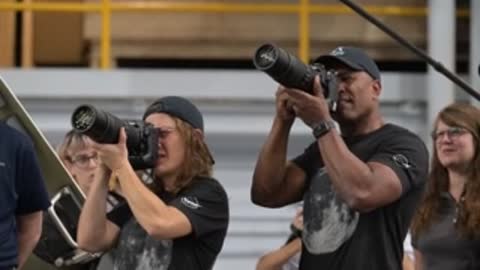 Astronauts practicing holding large telephoto lenses in a training area.