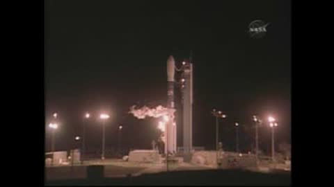 Static wide shot of a space rocket standing on the launch pad at night.