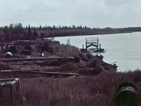 Riverbank with industrial equipment, wooden structures, and water view