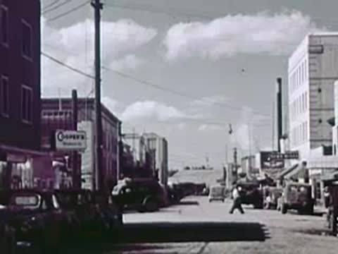 A town street scene with buildings and distant vehicles.