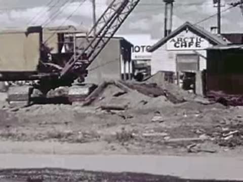 A construction excavator and a bulldozer moving earth near a cafe.