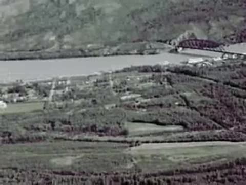 An aerial view of a river, bridge, and surrounding landscape.