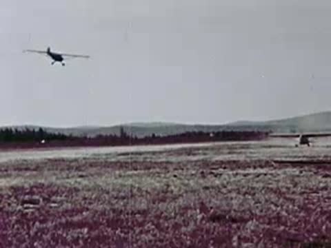 Small single-engine floatplane taking off from a grassy airfield