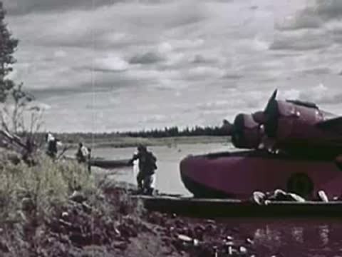 Floatplane pulled up onto a riverbank with people standing nearby