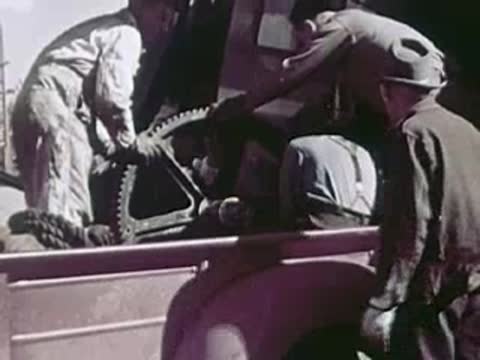 Close-up of men lifting heavy mechanical parts into the back of a truck