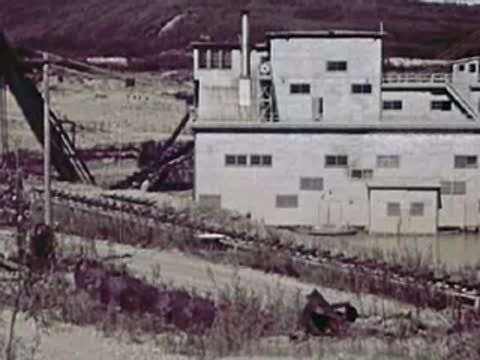 Large industrial building with multiple windows near a dirt road