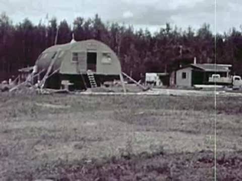 Nissen hut and small wooden buildings near a treeline