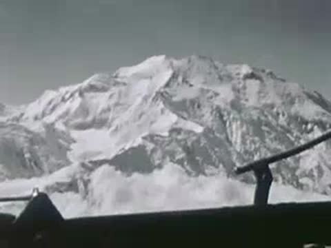 Snow-covered mountain range viewed from an airplane cockpit, aerial view, 1940s