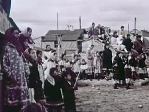 A crowd of people gathered outdoors near buildings, community, 1940s
