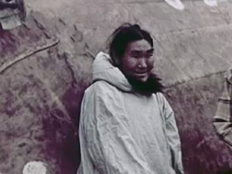 An Indigenous person smiling in a light-colored parka.